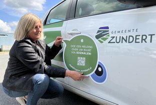 Wethouder Kools plakt een magneet op de auto.