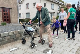 Man met rollator doet een oefening van de fitroute.