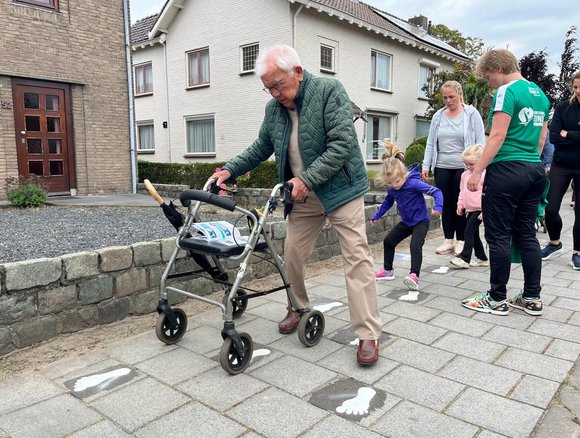 Man met rollator doet een oefening van de fitroute.