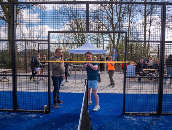 Wethouder Wesley van Steen knipt een lintje door bij de feestelijke opening van 2 nieuwe padelbanen.