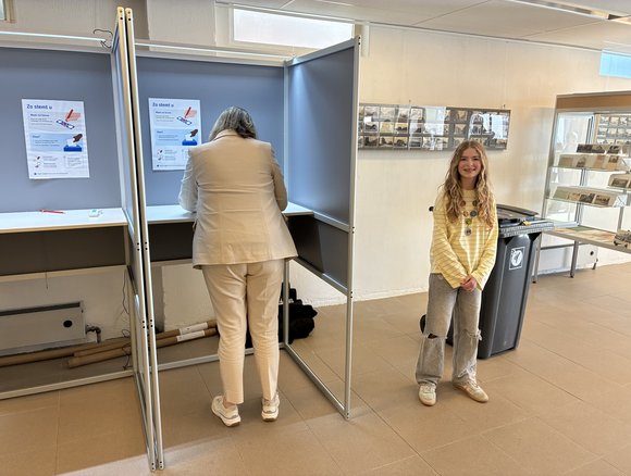 Burgemeester Vermue en kinderburgemeester Jot bij het stemhokje.